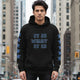 Oversized urban streetwear hoodie it is what with bold text in a city setting, showcasing resilience and self-acceptance.