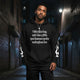 Model wearing oversized black urban hoodie with unique text design in urban alley setting.